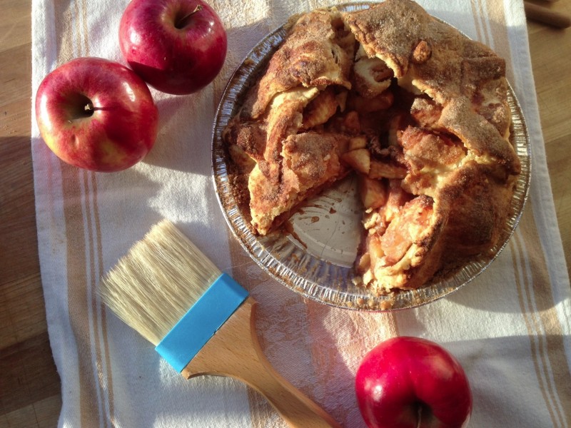 apple pie with slice taken out surrounded by apples