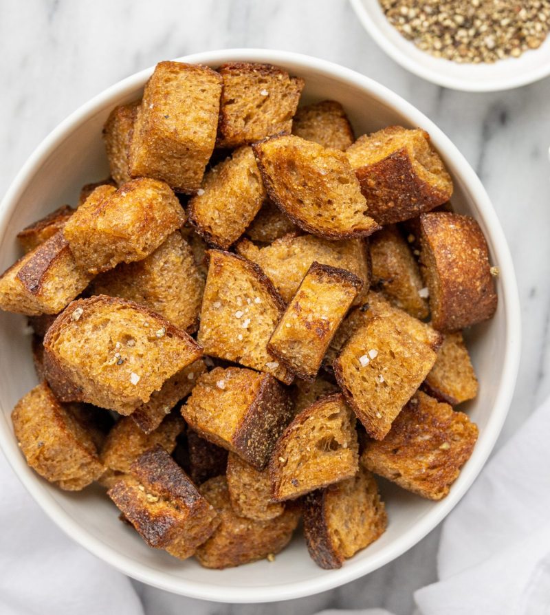 croutons in a white bowl with small dishes of salt and pepper