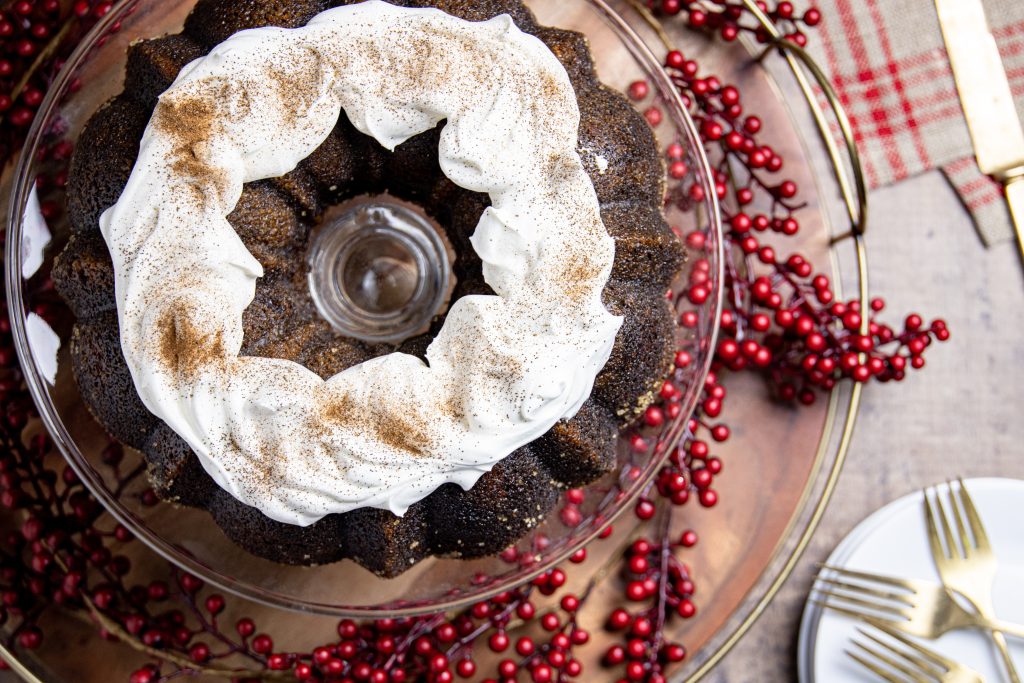 overhead view of a gingerbread coffee cake with red berries and whipped cream