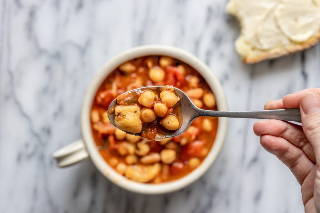 overhead view of a bowl of semolina dumpling soup with a spoon lifting some out