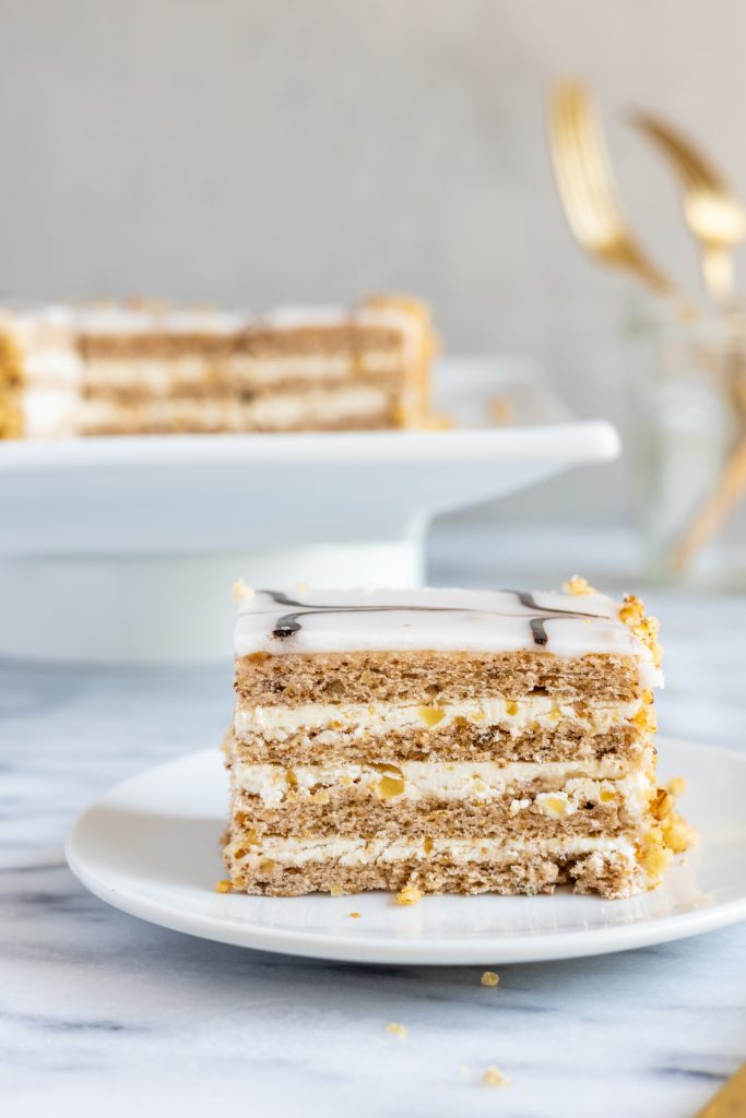 slice of an Esterhazy Torta with the full cake on a stand behind it