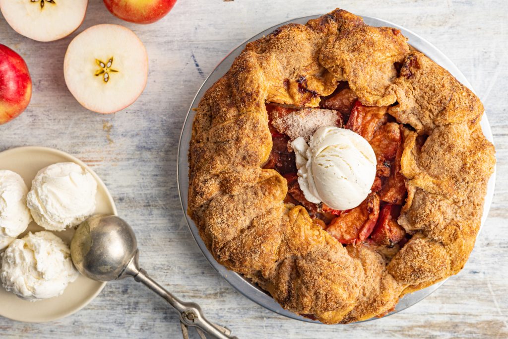overhead view of a rustic apple pie with a scoop of vanilla ice cream on top