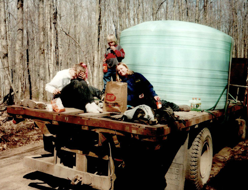kids on the back of a truck with a tank of maple syrup