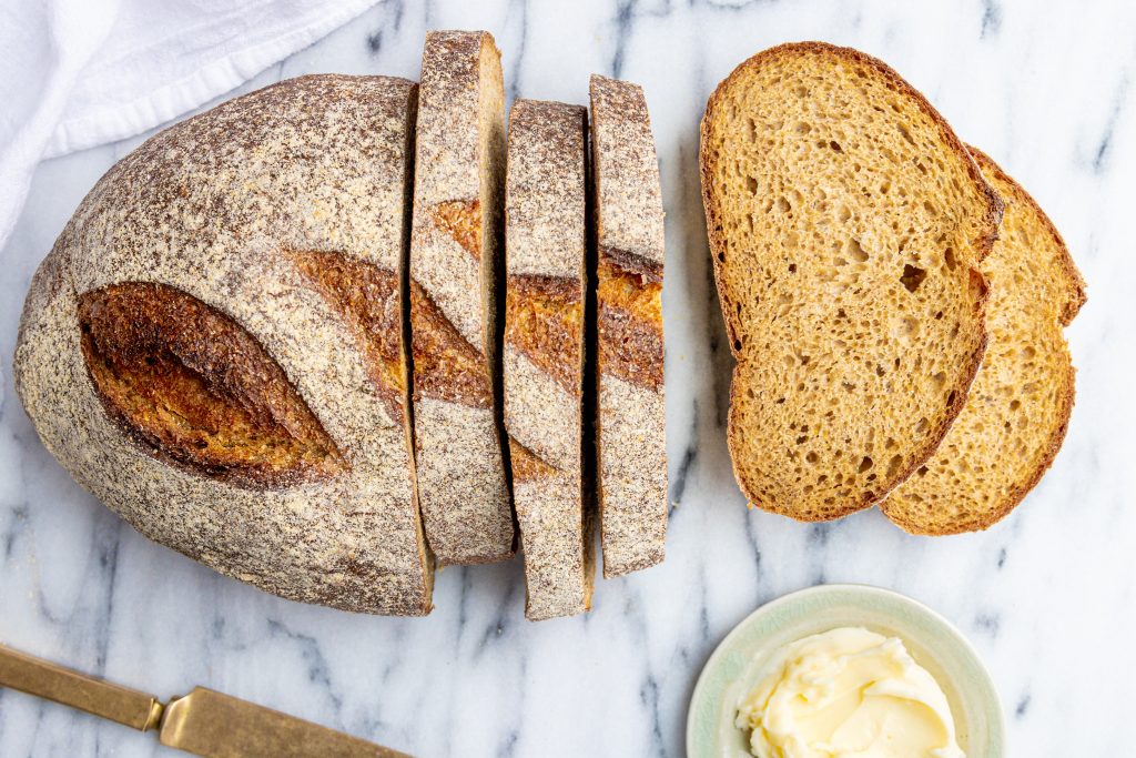 a loaf of Roadhouse Bread partially sliced with a couple of slices tipped over