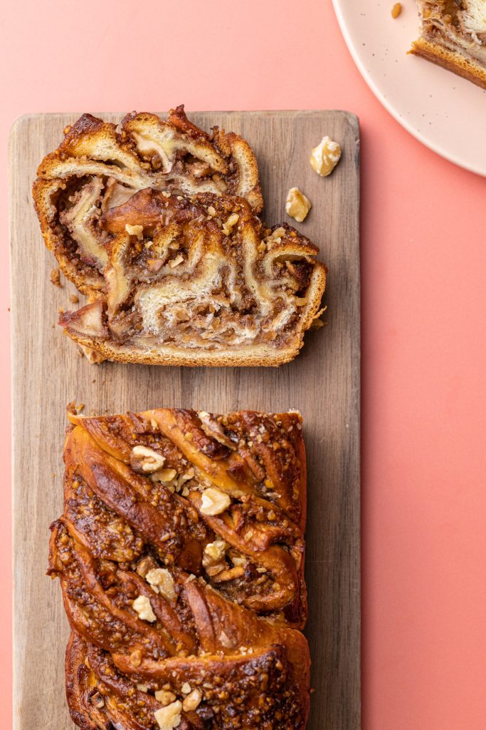 overhead view of Eve's Apple Babka on a wooden cutting board with two slices cut and another on a plate