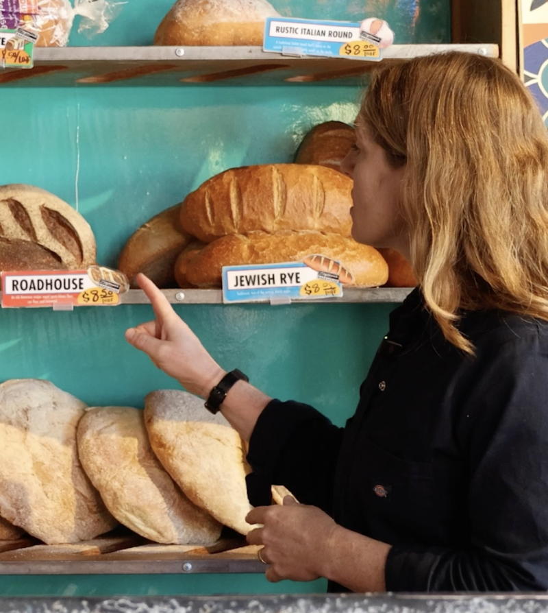 a woman points at a loaf of bread