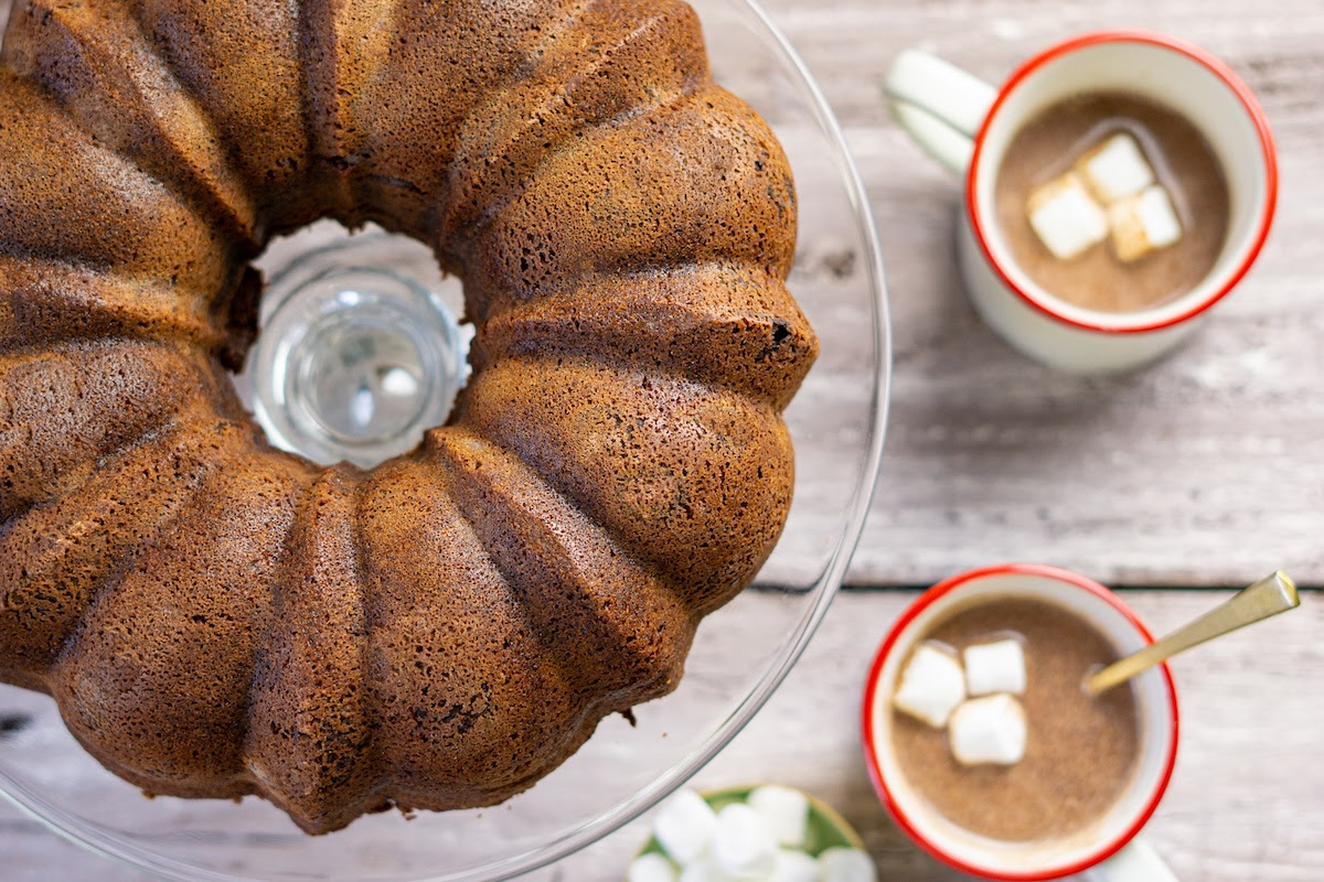hot cocoa coffee cake and two mugs of cocoa with marshmallows in them