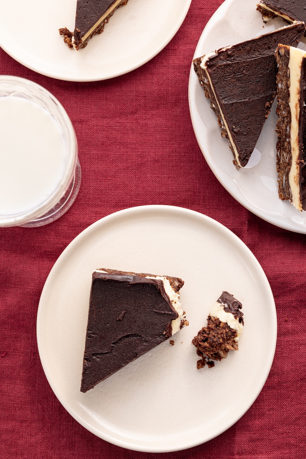 nanaimo bars on dessert plates on a red table cloth